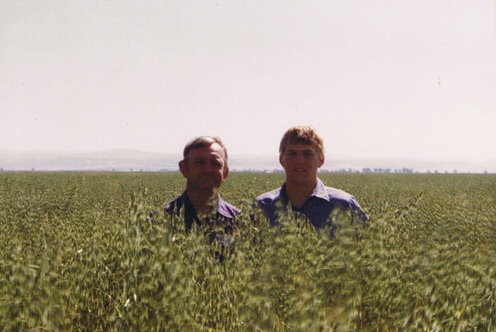 Harlan and Bryce Lundberg, father and son, stand in a field of cover crops circa the 1980s.