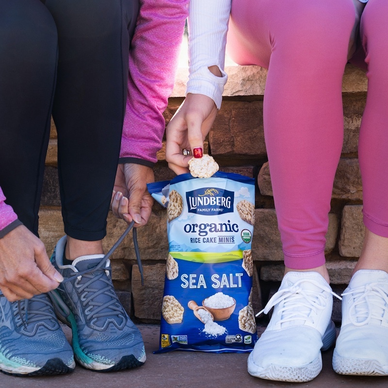 Two women tie their shoes and enjoy Sea Salt Rice Cake Minis before their workout.